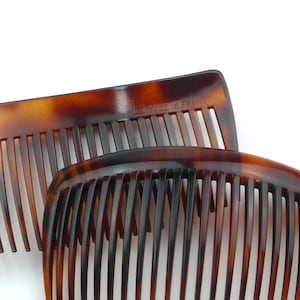 May include: Two tortoise shell combs with fine teeth. The combs are a warm brown color with darker brown marbling. The text "MADE IN FRANCE" is visible on one comb.