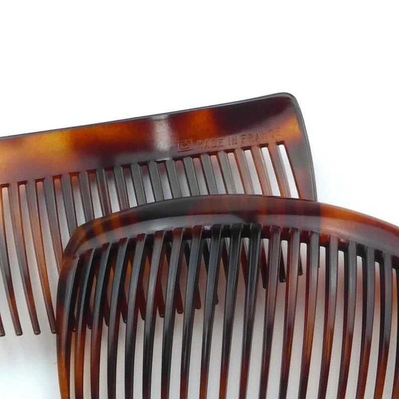 May include: Two tortoise shell combs with fine teeth. The combs are a warm brown color with darker brown marbling. The text "MADE IN FRANCE" is visible on one comb.