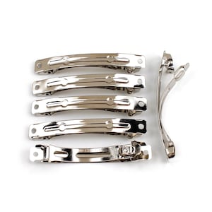 May include: Seven silver metal hair clips. All the clips are the same size and shape, with a curved design. They have a smooth, shiny finish.