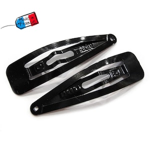 Könnte beinhalten: Zwei schwarze Haarklammern aus Metall. Die Klammern sind oval geformt und haben eine strukturierte Oberfläche. Die Klammern sind in Frankreich hergestellt.