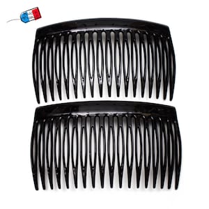 Pode incluir: Dois pentes de cabelo pretos com a parte superior curva e dentes espaçados uniformemente. Os pentes são feitos de um material brilhante e estão colocados sobre um fundo branco. Uma pequena etiqueta no canto superior esquerdo diz "Made in France."