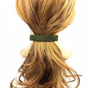 May include: A green glitter hair clip. The clip is rectangular and has a sparkly finish.