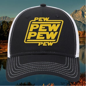 May include: Black and white trucker hat featuring the word "PEW" in yellow block letters. The hat has a curved brim with white stitching and a mesh back. The text is inside a yellow rectangle.