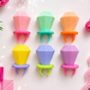 May include: Six plastic ring-shaped wall hooks in a diamond shape, arranged in two rows of three. The colors include pink, mint green, orange, yellow, light purple, and magenta. Each hook features a faceted top and a circular base ring.
