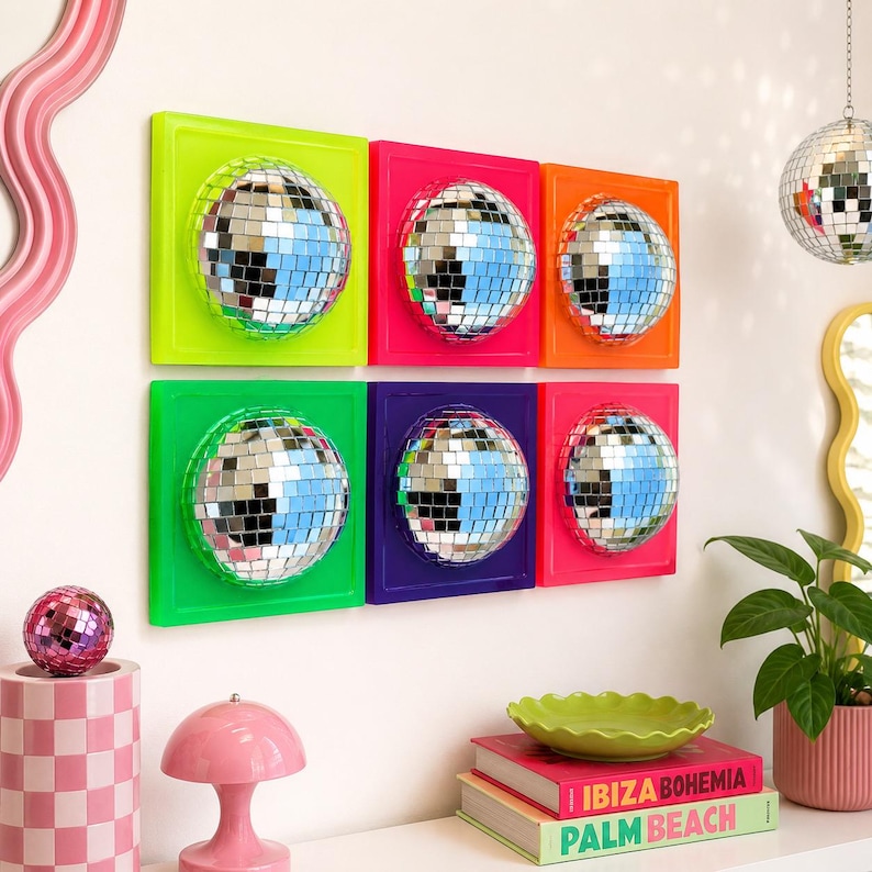May include: A set of six square wall panels, each featuring a centered, reflective disco ball made of small mirrored tiles. The frames are painted in vibrant neon colors including lime green, hot pink, orange, bright green, purple, and red.