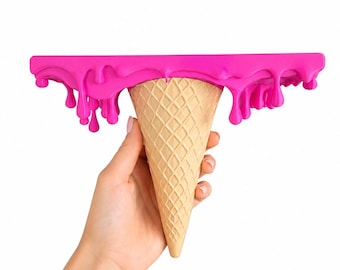 Puede incluir: Un estante de pared con forma de cono de helado invertido con una superficie superior plana. La parte superior presenta un color rosa intenso con un efecto de goteo realista a lo largo de los bordes, mientras que la base es un cono de barquillo beige.