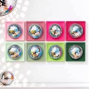 May include: Eight square wall-mounted frames, each containing a reflective silver disco ball. The frames are arranged in two rows of four, featuring a gradient of pink, magenta, light green, and dark green colors. A disco ball is also visible.