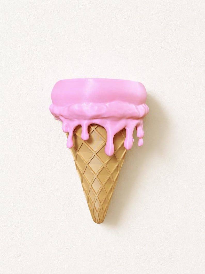 May include: A wall-mounted ice cream cone sculpture featuring a tan, diamond-patterned waffle cone base topped with a thick layer of smooth, bright pink ice cream that appears to be melting down the sides of the cone in rounded drips.