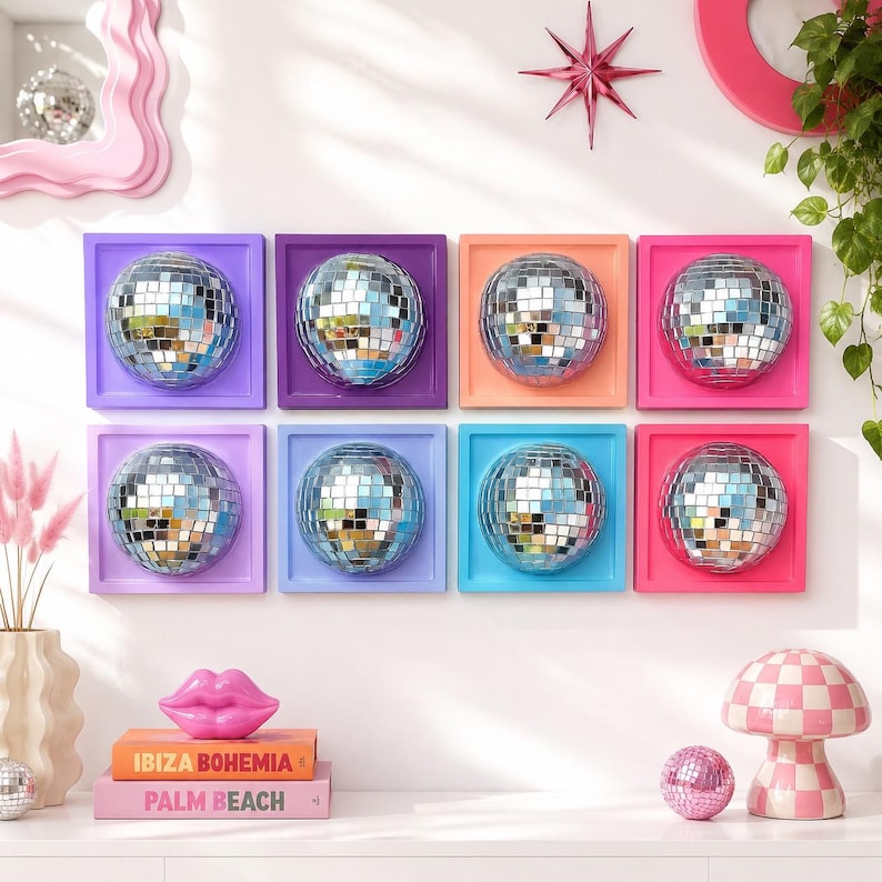 May include: Eight square wall art pieces, each featuring a central silver mirrored disco ball mounted on a solid-colored frame in shades of purple, orange, pink, and blue. The frames are arranged in two rows of four on a white wall.