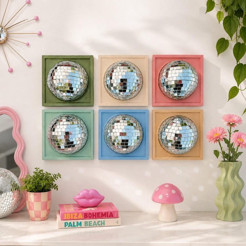 Pode incluir: Uma decora&ccedil;&atilde;o de parede com seis molduras quadradas, cada uma contendo uma bola de discoteca prateada. As molduras s&atilde;o pintadas em verde-oliva, creme, coral, verde-menta, azul-claro e bege. O arranjo forma uma grade de duas linhas e tr&ecirc;s colunas.