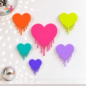 May include: A collection of six heart-shaped wall decorations in various sizes and colors, including orange, neon yellow, hot pink, teal, purple, and violet, each featuring a dripping paint effect along the bottom edge.