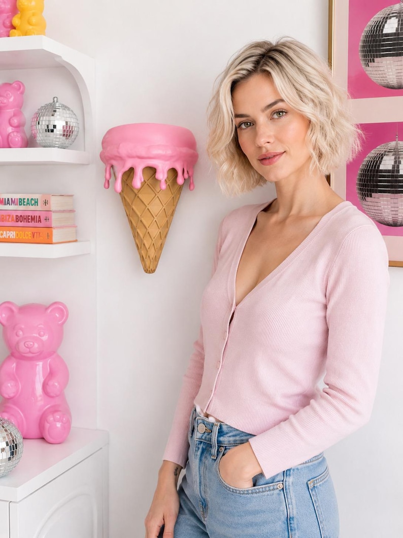 May include: A light pink long-sleeve cardigan with a V-neckline and a ribbed texture, worn with blue denim jeans. The cardigan features a button-down front closure and a fitted silhouette that reaches the waistline, providing a simple look.