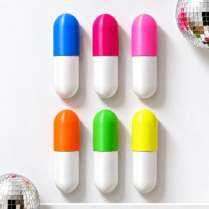 May include: Six pill-shaped objects arranged in two rows, each featuring a white base and a brightly colored top in blue, pink, magenta, orange, green, or yellow. Two reflective disco balls are positioned at the top right and bottom left corners.