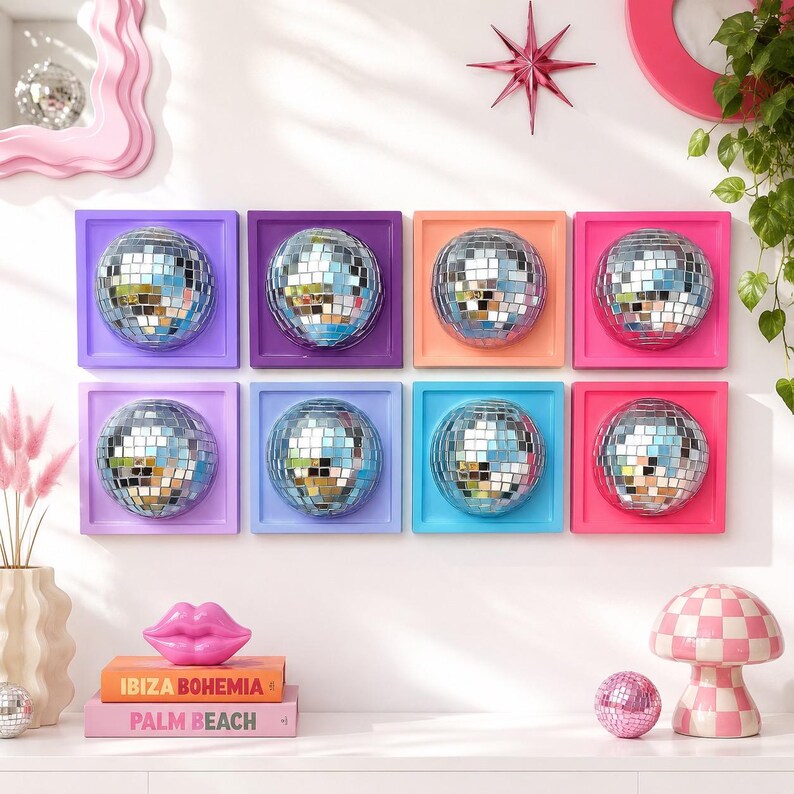 Pode incluir: Oito pe&ccedil;as de arte de parede quadradas, cada uma com uma esfera central de globo de discoteca espelhado montada numa moldura de cor s&oacute;lida em tons de roxo, laranja, rosa e azul. Abaixo, dois livros empilhados intitulados IBIZA BOHEMIA e PALM BEACH.