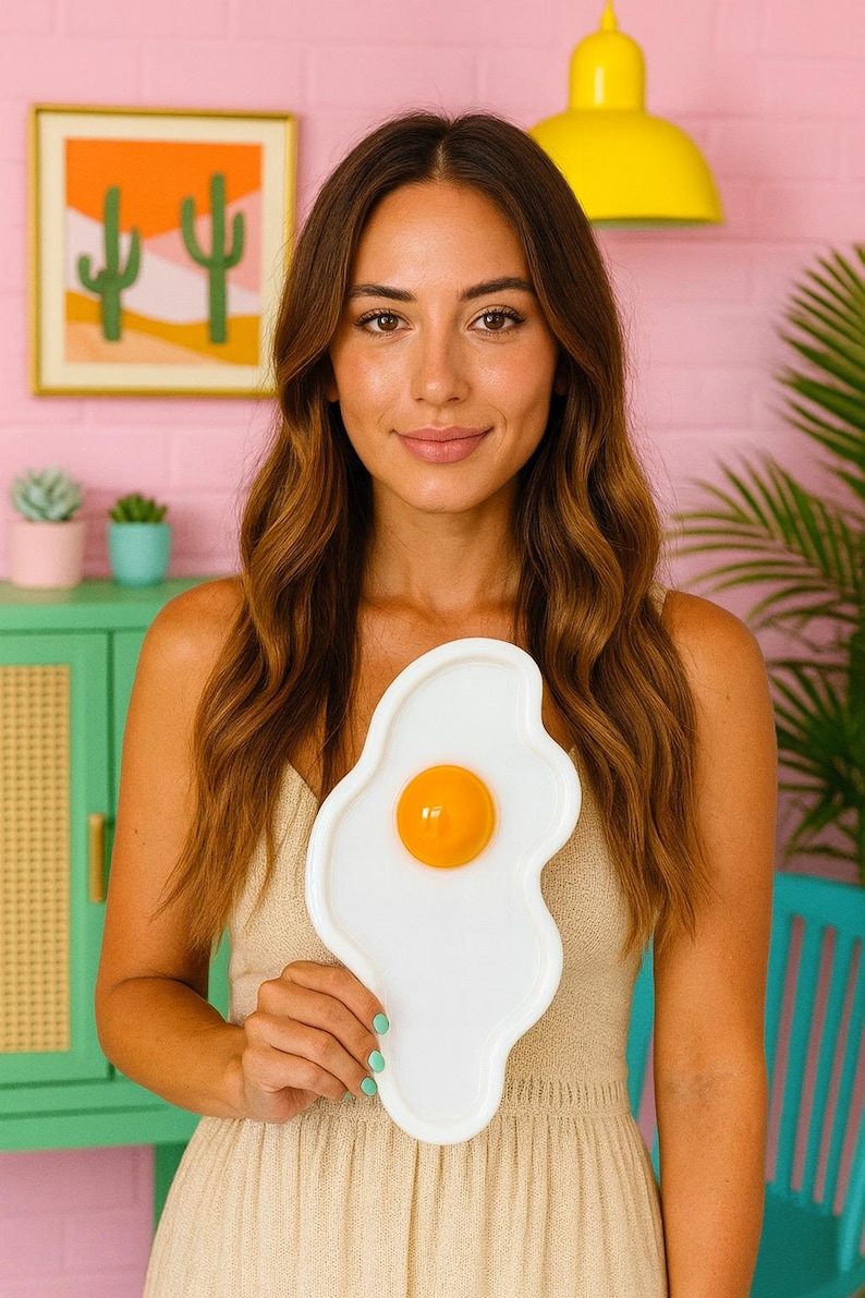 Puede incluir: Una bandeja blanca de forma irregular dise&ntilde;ada para parecerse a un huevo frito, con un centro circular naranja brillante, elevado y lustroso que imita una yema. La bandeja tiene un per&iacute;metro curvo y suave con un dise&ntilde;o limpio.