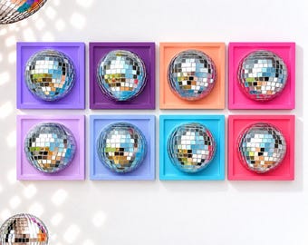 May include: Eight square wall-mounted frames in various colors, each containing a centered, reflective silver disco ball. The frames are arranged in two rows of four, featuring shades of purple, orange, pink, and blue. A separate disco ball sits below.