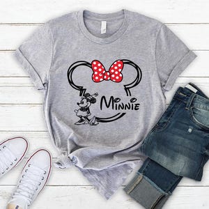 May include: Gray t-shirt with a black and white illustration of Minnie Mouse with a red bow and the text "Minnie" underneath.
