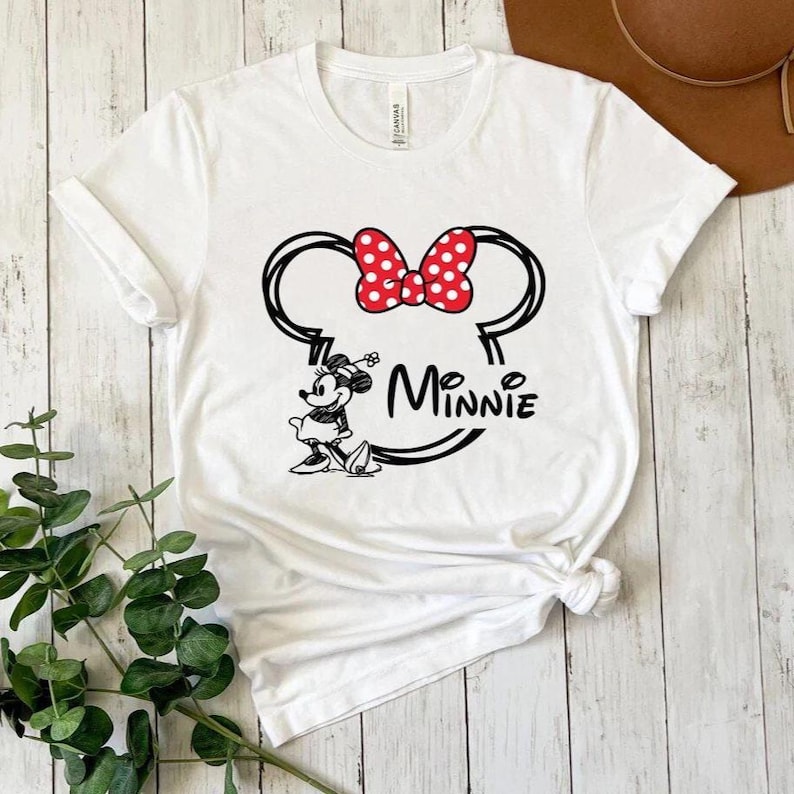 May include: White t-shirt with a black and white graphic of Minnie Mouse with her signature red polka dot bow. The text "Minnie" is written below the graphic.