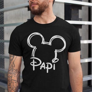 May include: Black t-shirt with a white outline of Mickey Mouse ears and the word "Papi" underneath.