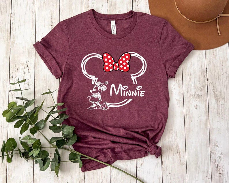 May include: Burgundy t-shirt with a white outline of Minnie Mouse's head and the word "Minnie" underneath. Minnie Mouse has a red bow with white polka dots.