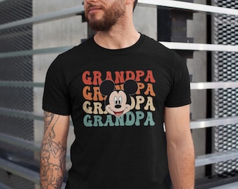 May include: Black t-shirt with a retro-style graphic of Mickey Mouse's head and the word "Grandpa" repeated four times in a rainbow color scheme.