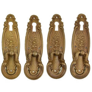 Könnte beinhalten: Satz von vier antiken goldfarbenen Türgriffen mit verzierten Blumendesigns und Schlüssellöchern.