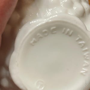 May include: A close-up of a white ceramic object with a textured surface. The base of the object has the words "MADE IN TAIWAN" stamped on it. The object has a scalloped edge.