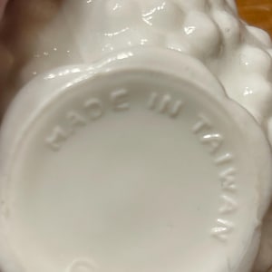 May include: A close-up of the bottom of a white ceramic object with a textured, floral-like design. The words "MADE IN TAIWAN" are embossed in a circular pattern.