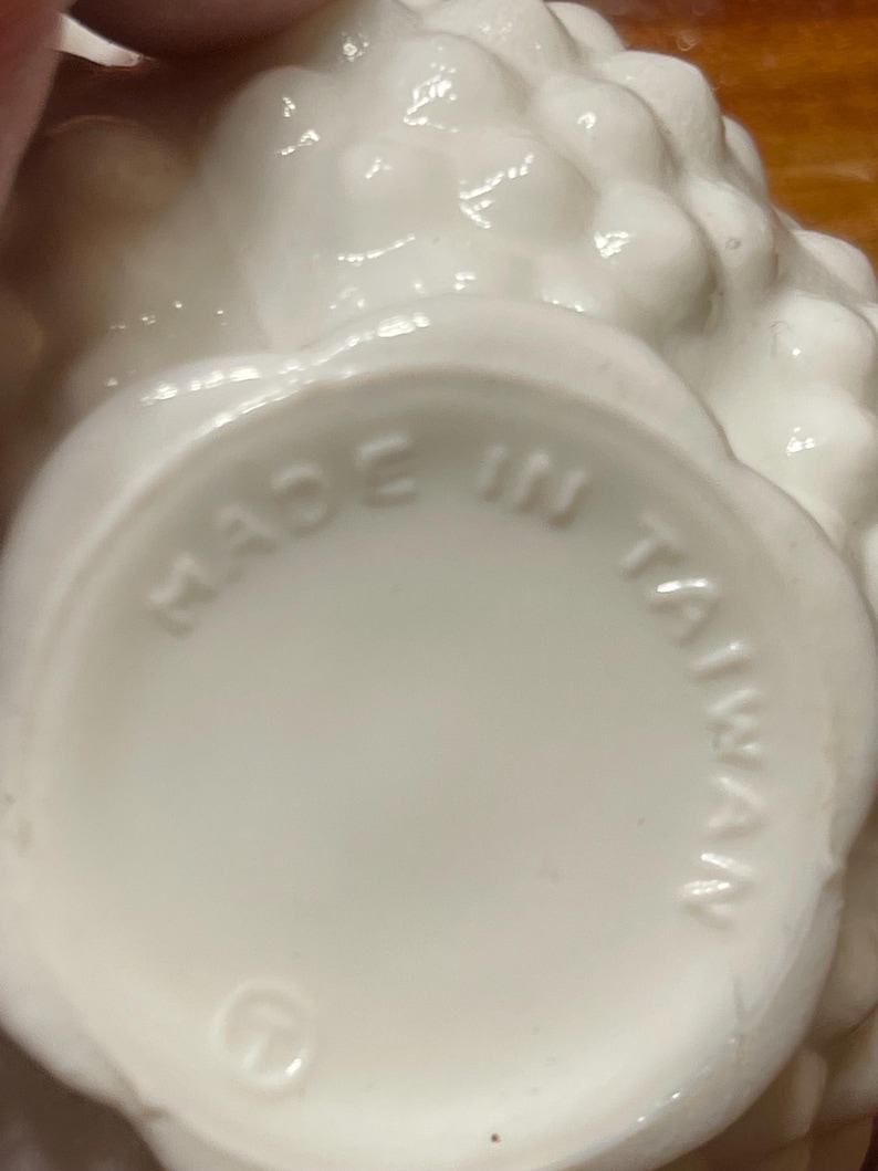 May include: A close-up of the bottom of a white ceramic object with a textured, floral-like design. The words "MADE IN TAIWAN" are embossed in a circular pattern.