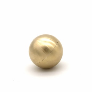 May include: A solid brass sphere with a smooth, polished finish. The sphere is a decorative object.