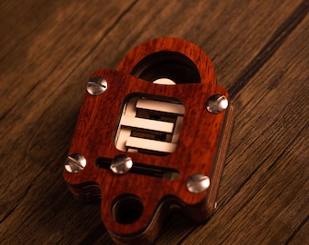 May include: A wooden puzzle in the shape of a padlock with a red mahogany finish. The puzzle has a series of interlocking pieces that must be manipulated to open the lock.