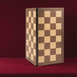 Könnte beinhalten: Ein Schachbrett aus Holz mit einem karierten Muster in Dunkelbraun und Hellbraun. Das Brett ist in dunklem Holz gerahmt und vor einem tiefroten Hintergrund platziert. Das Schachbrett ist ein klassisches Spiel.