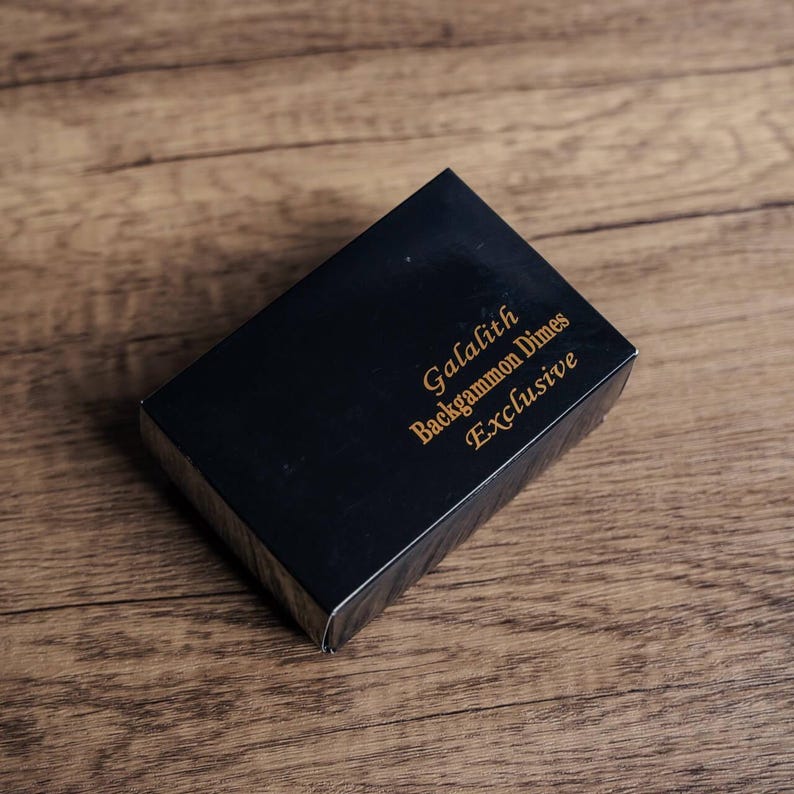 Puede incluir: Caja negra con letras doradas que dicen "Galalith Backgammon Dimes Exclusive".