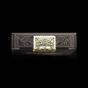 Op de afbeelding: Een zwarte speelkaartenbox met gouden accenten. De doos heeft de woorden "Not" en "NYC" aan de voorkant en een gouden stempel met de woorden "Stranger Strange" en "14" erop.