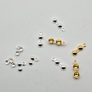 Può includere: Una collezione di componenti per gioielli color argento e oro. I componenti includono piccoli connettori a tre perline e connettori a due perline. I connettori vengono utilizzati per la creazione di gioielli e l'artigianato. Lo sfondo è di colore grigio chiaro.