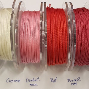 Op de afbeelding: Zes spoelen met koord in verschillende tinten rood, roze en wit. De spoelen zijn gelabeld met "weiß", "Creme", "Dunkel-rosa", "Rot", "Dunkel-rot" en "Granat-rot".