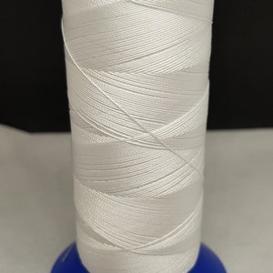 Pu&ograve; includere: Un'bobina di filo bianco avvolta attorno a una bobina di plastica blu.