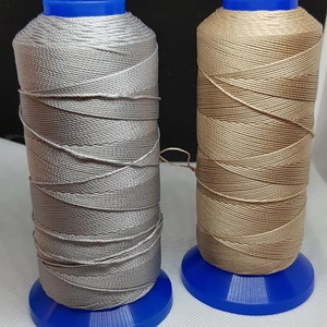Pu&ograve; includere: Due bobine di filo, una argentata e una beige, sono avvolte su bobine di plastica blu. Il filo &egrave; un tipo di filo cerato utilizzato per cucire la pelle.