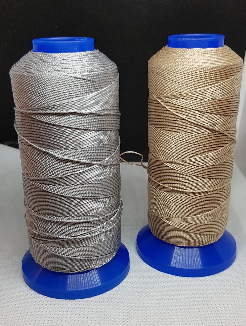 Pu&ograve; includere: Due bobine di filo, una argentata e una beige, sono avvolte su bobine di plastica blu. Il filo &egrave; un tipo di filo cerato utilizzato per cucire la pelle.