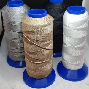 Pu&ograve; includere: Quattro bobine di filo di diversi colori: argento, beige, nero e bianco. Ogni bobina &egrave; su una base di plastica blu.