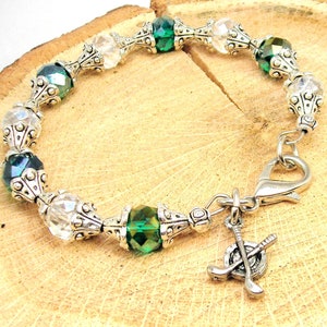 May include: A silver and green crystal bracelet with a golf club charm. The bracelet features alternating clear and green crystals with silver accents.