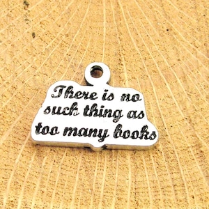 May include: Silver charm shaped like an open book with the text "There is no such thing as too many books".