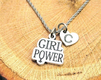 May include: Silver necklace with a charm that says "Girl Power" and a heart charm with the letter "C" engraved on it.