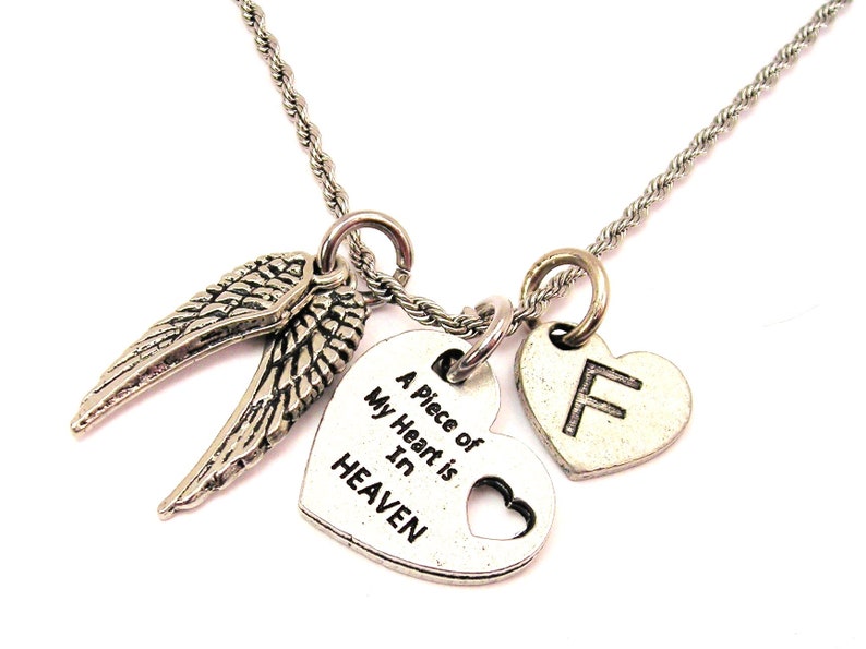 K&ouml;nnte beinhalten: Silberne Halskette mit drei Anh&auml;ngern: ein Herz mit der Aufschrift "A piece of my heart is in HEAVEN", ein Herz mit dem Buchstaben "F" und ein Paar Engelsfl&uuml;gel.