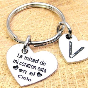 May include: Silver heart-shaped keychain with the inscription "La mitad de mi corazon esta en el Cielo" and a smaller heart-shaped charm with the letter "V" engraved on it.
