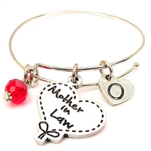 Può includere: Braccialetto rigido in argento con un ciondolo a forma di cuore che dice "Mother in Law" e un piccolo ciondolo a forma di cuore con la lettera "O". Il braccialetto ha anche una perla di cristallo rossa.