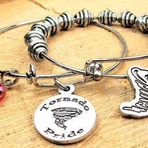 May include: Two silver charm bracelets with a red crystal charm, a silver charm with the words "Tornado Pride" and a silver tornado charm.