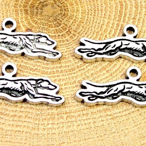 May include: Four silver-toned metal charms shaped like a running greyhound dog. Each charm has a loop at the top for attaching to a necklace or bracelet.