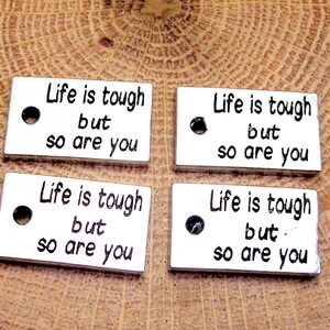 May include: Four silver metal tags with the text "Life is tough but so are you" on each tag.