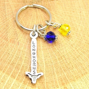 May include: Silver keyring with a Longhorns charm, a blue crystal bead, and a yellow crystal bead.